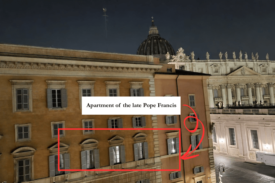 Nighttime view of the Apostolic Palace in Vatican City, with a red box and arrows marking a lit window. A label above reads “Apartment of the late Pope Francis,” pointing to a section of the historic building near the dome of St. Peter’s Basilica.