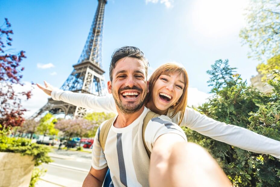 Happy couple of tourists taking selfie picture in front of Eiffel Tower in Paris, France
