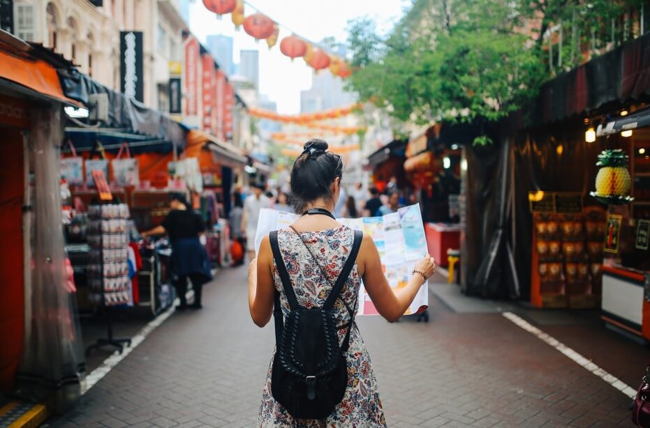 Young solo traveler woman in Singapore street market checking the map