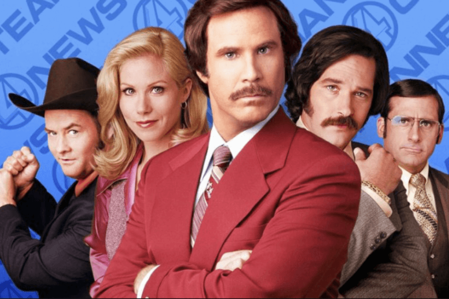 Five characters from the comedy film Anchorman pose confidently against a blue backdrop featuring the Channel 4 News logo. The central figure wears a red suit with a serious expression, flanked by colleagues with retro hairstyles and outfits, including a woman in pink and men with mustaches and glasses.