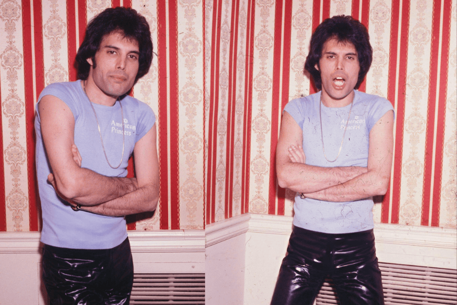 Side-by-side photos of Freddie Mercury standing against a red and gold vintage wallpaper, wearing a tight light blue shirt that reads “American Princess” and shiny black pants. In both shots, he has his arms crossed—posing seriously in one and with his mouth open expressively in the other.