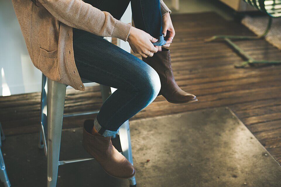 Woman putting on a high boot. Woman getting ready.