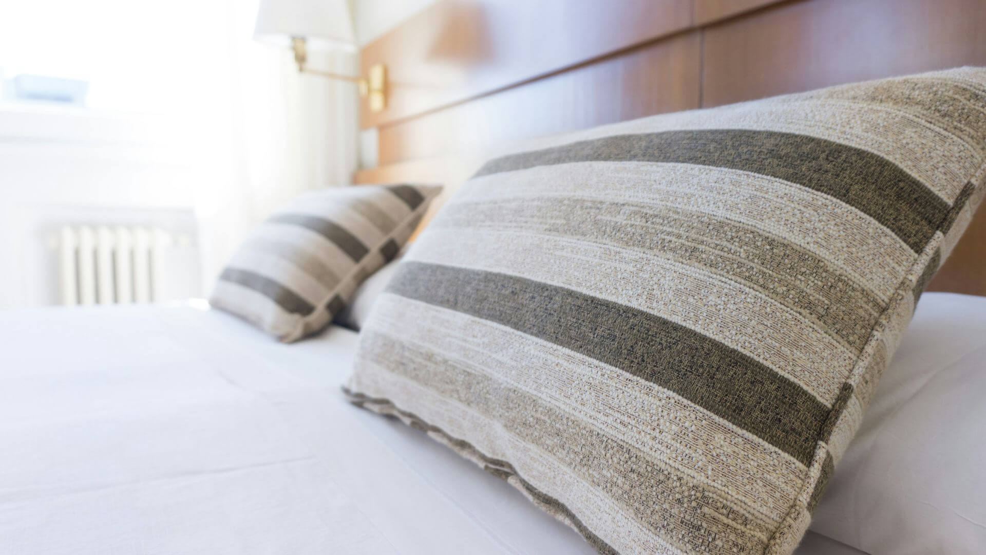 Gray and black throw pillows arranged neatly on a made bed in a cozy bedroom
