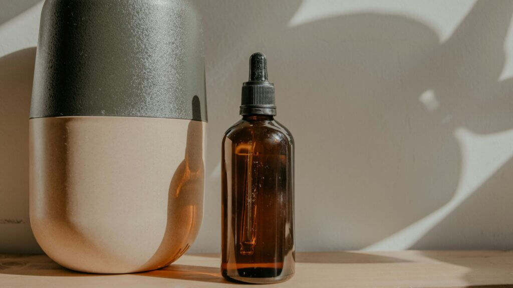 Clear glass fragrance bottle with white liquid on a wooden surface