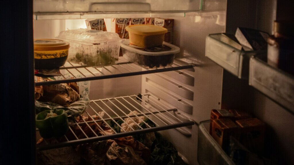 Open refrigerator fully stocked with fruits, vegetables, and jars
