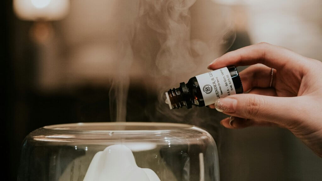 Person holding a small amber bottle labeled as essential oil