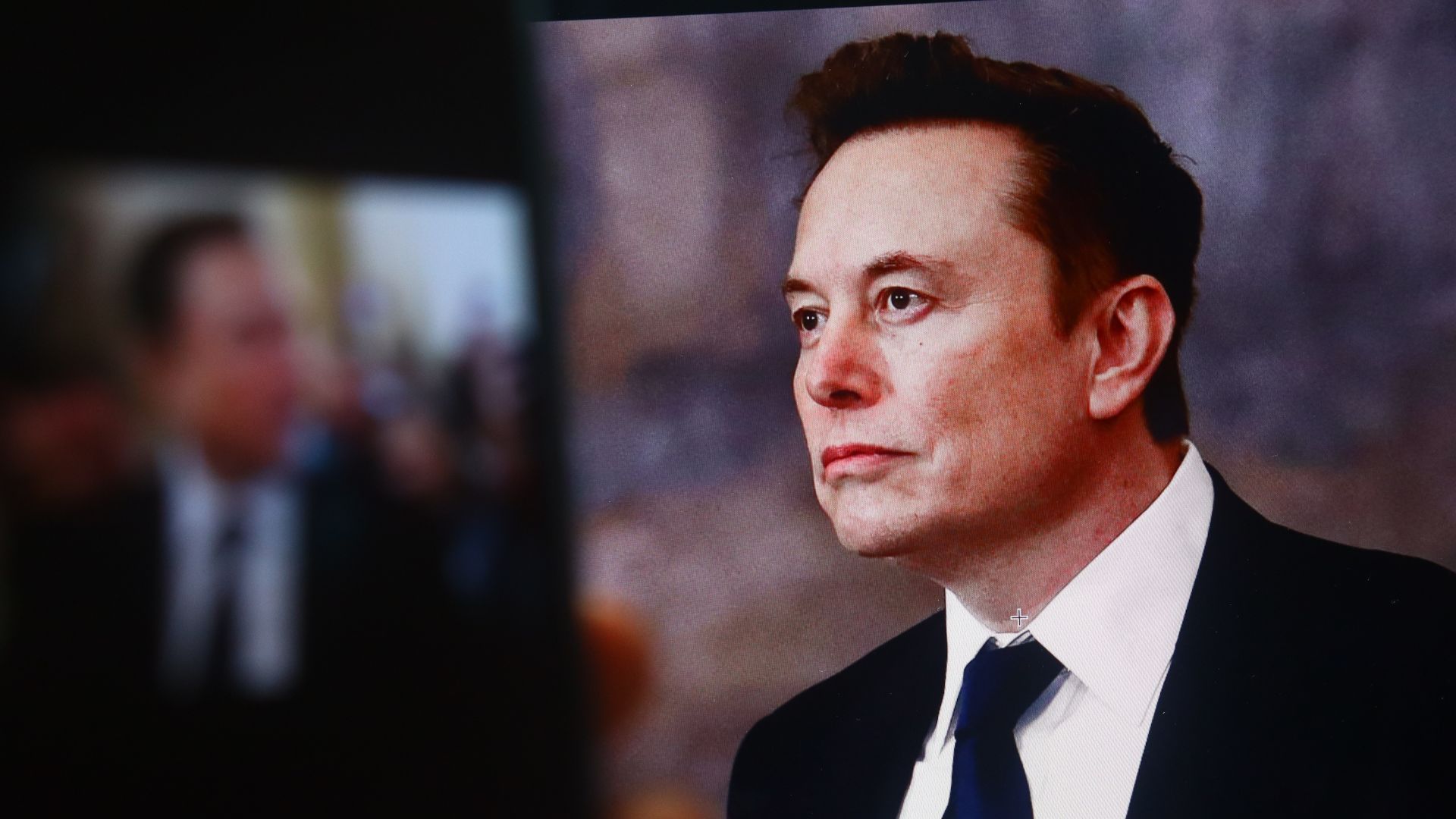 Elon Musk in a business suit posing for a photo