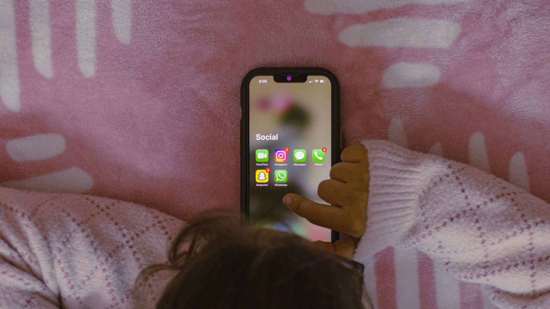 Person laying in bed holding a cell phone