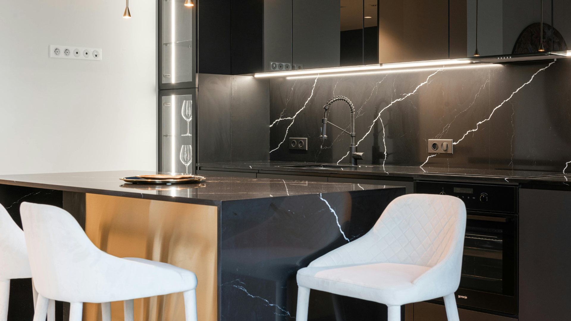 Bright kitchen with black lower cabinets, wood stools, and white upper cabinetry