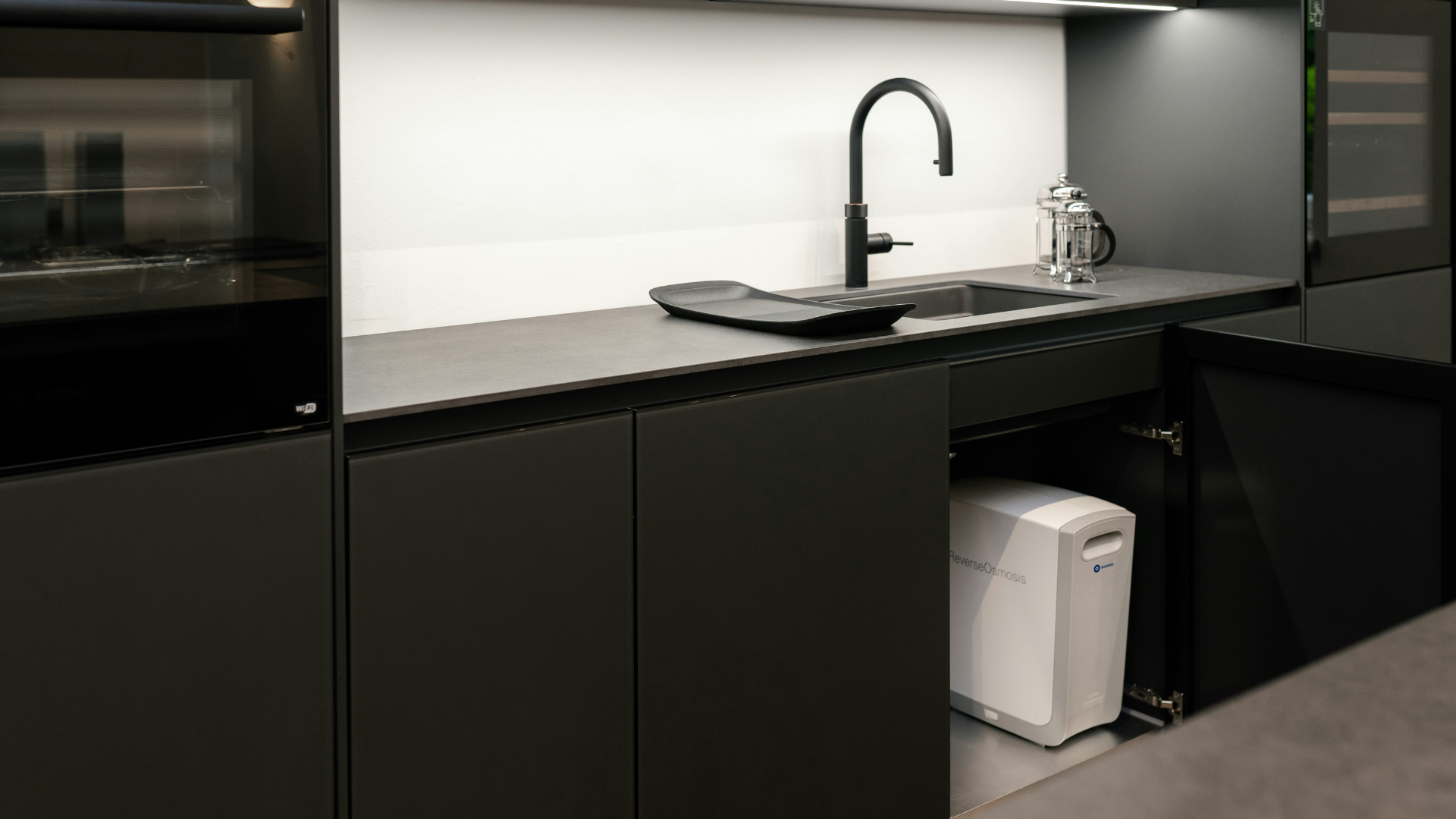 itchen featuring black lower cabinets, stainless steel appliances, and wooden details