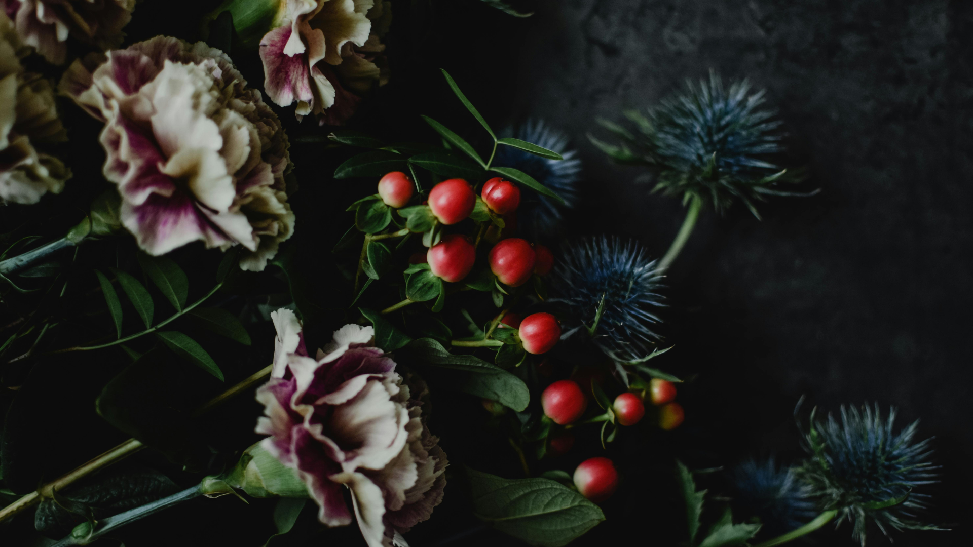 Cloves and eryngium flowers arranged on a wooden table near sunlight