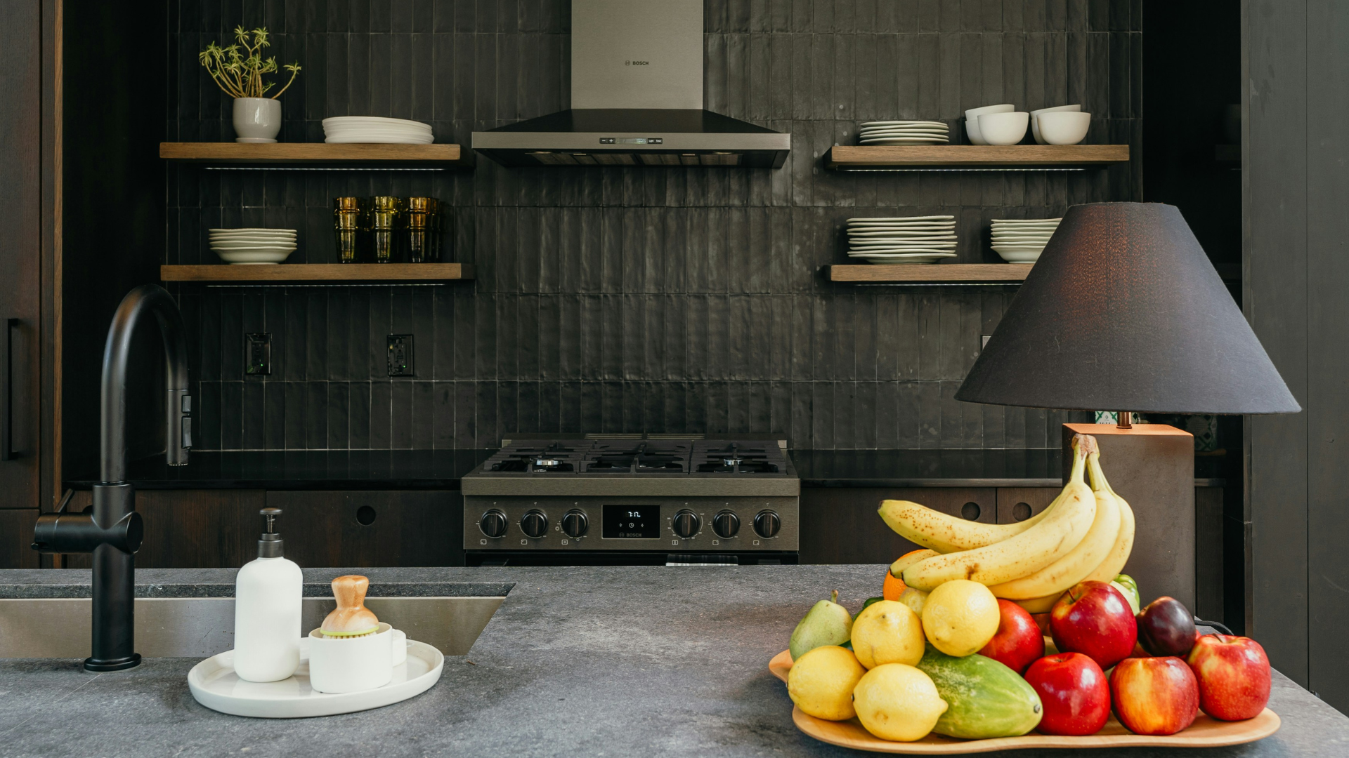 Kitchen with dark navy cabinets, wood accents, and a bowl of fruit on the counter