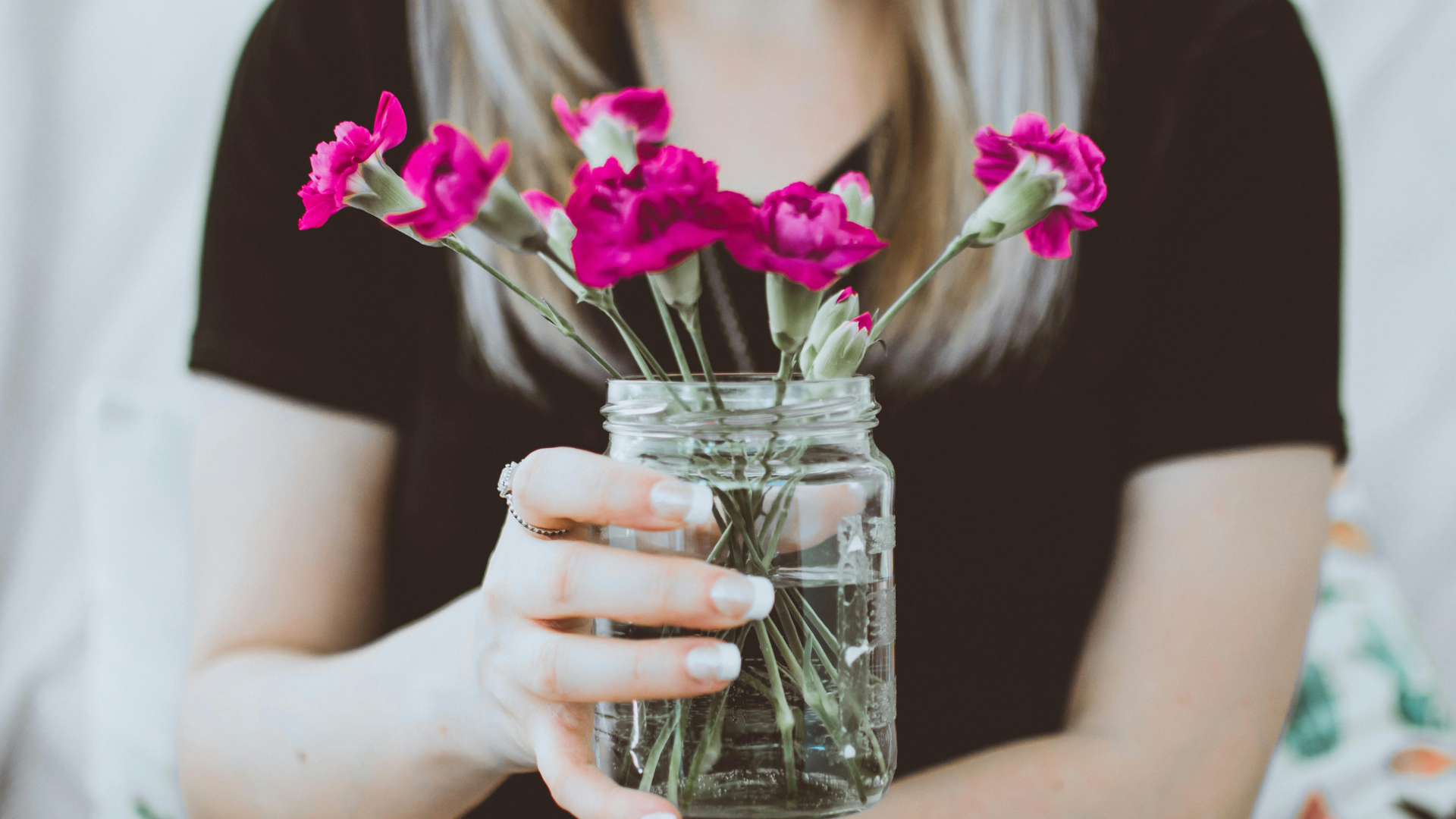 Person holding a mason jar filled with purple flowers