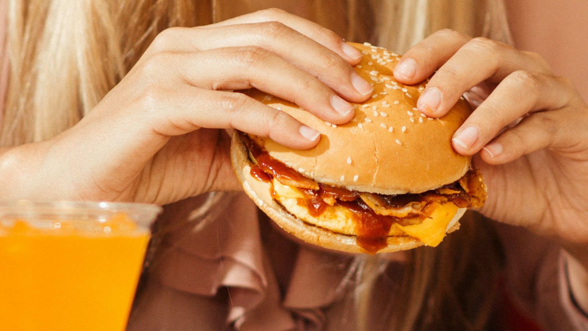 Woman holding a hamburger on a table