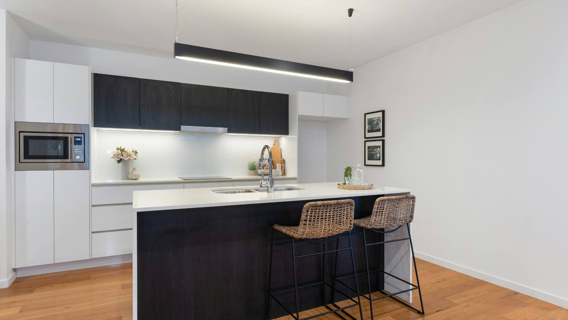 Kitchen with black cabinets, white countertops, and wood flooring
