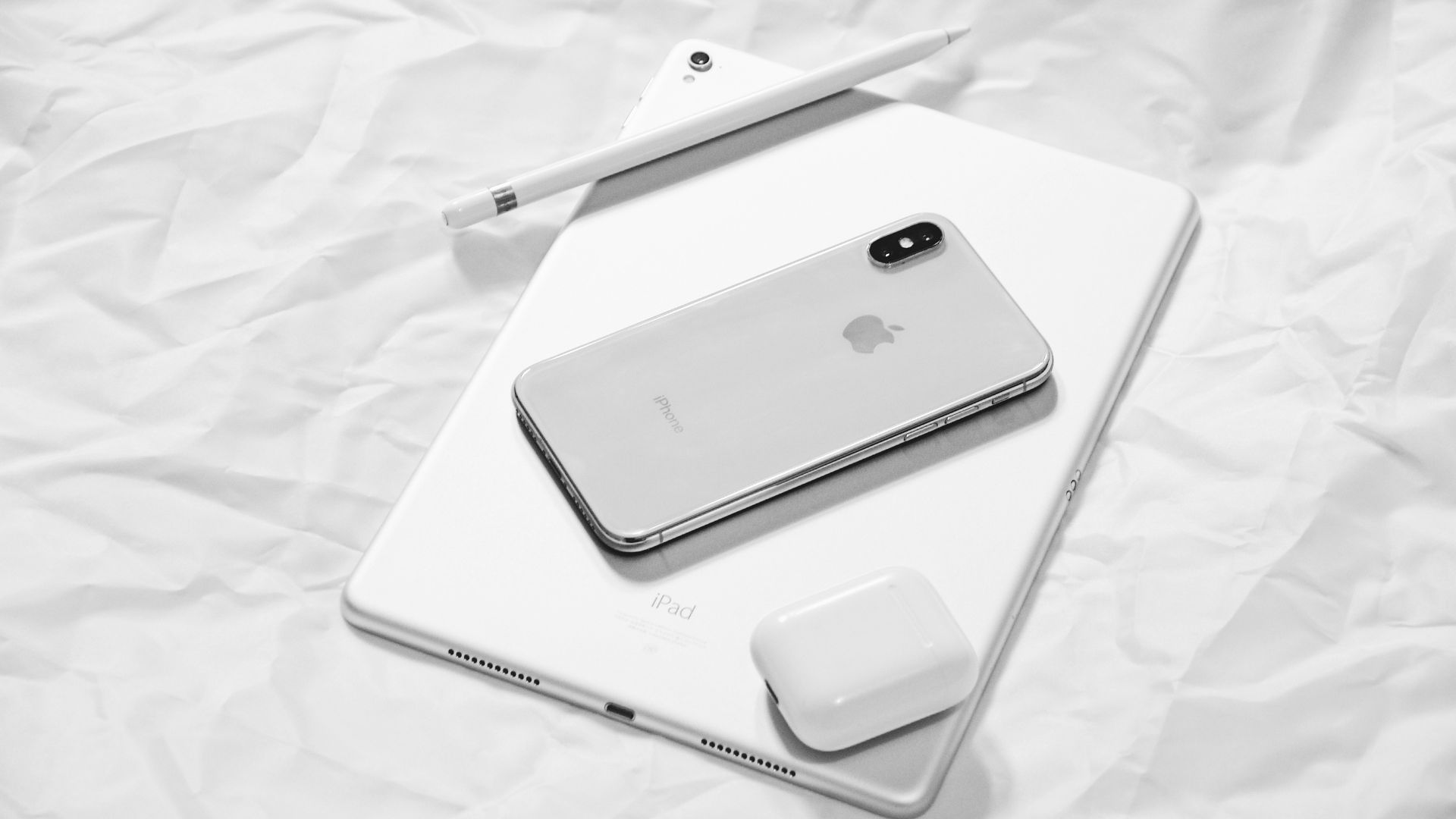 Silver iPhone X and silver iPad placed on a surface