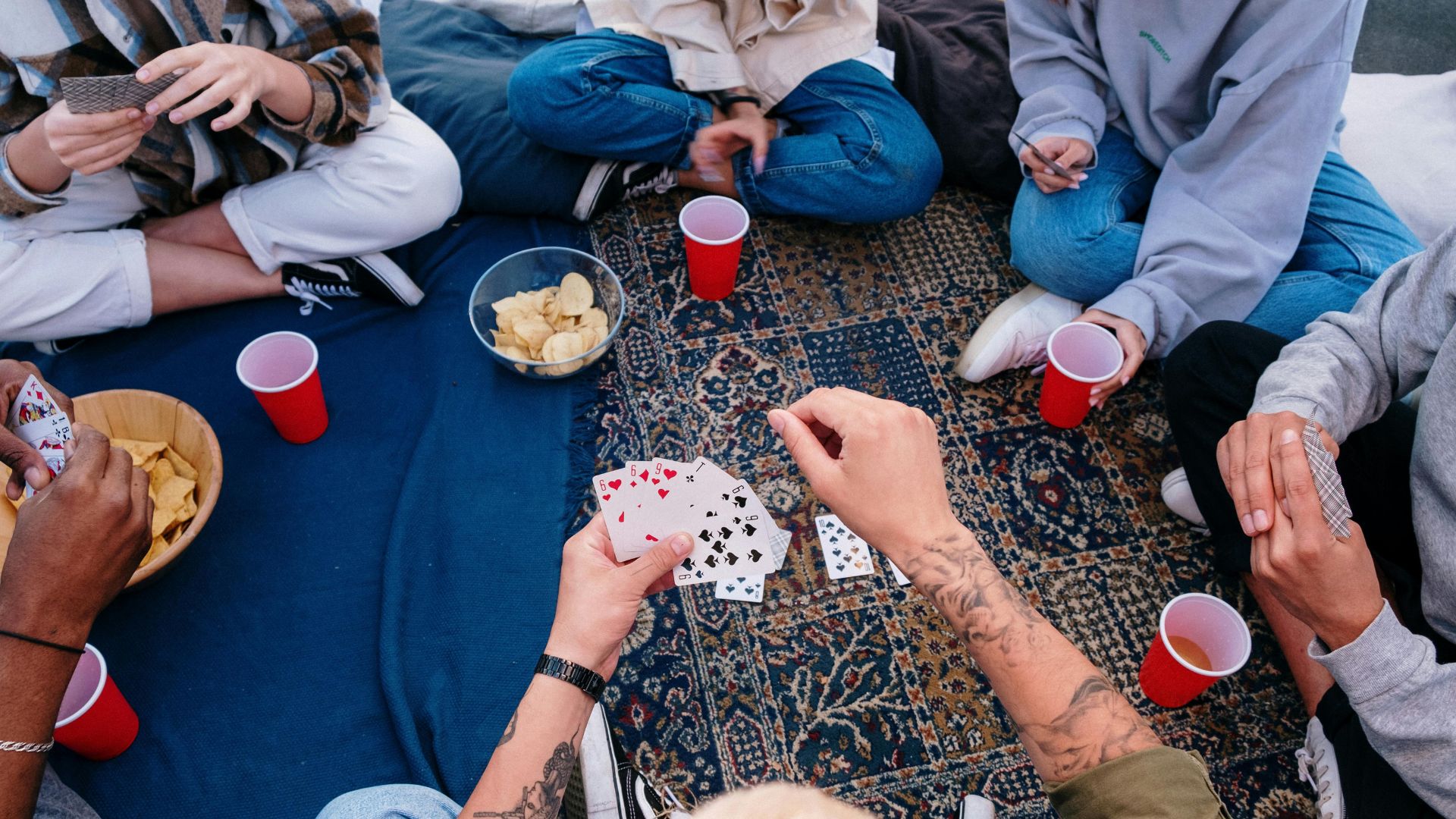 People sitting on floor with red and white ceramic mugs