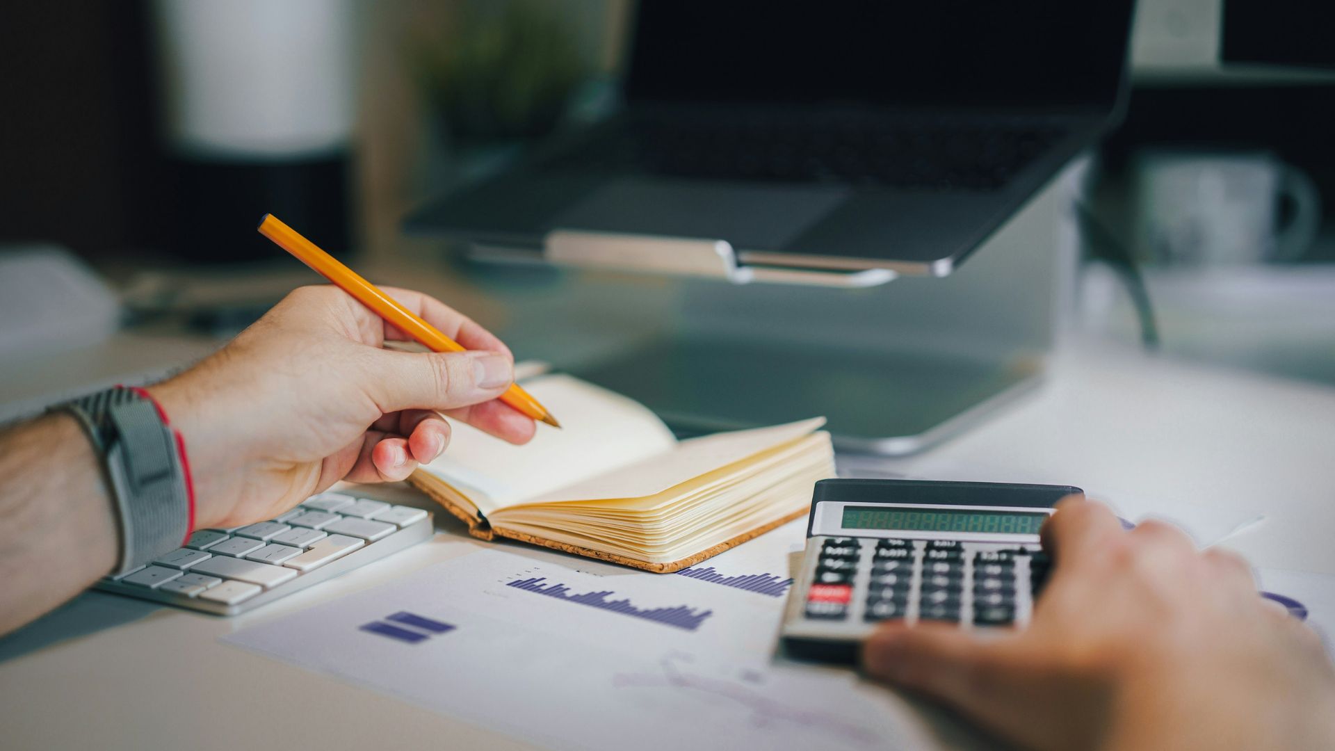 Person using calculator and notebook while working at desk