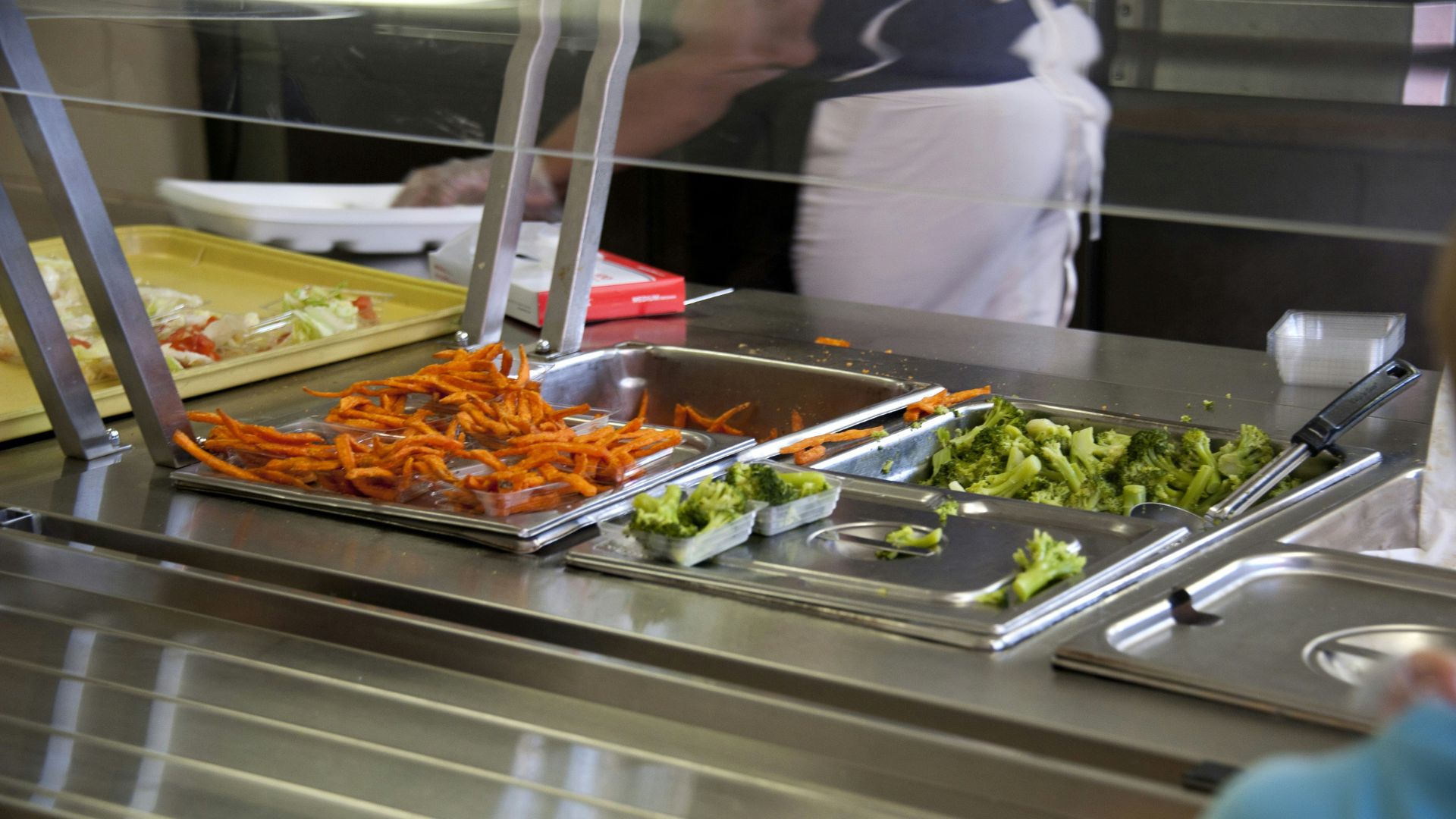 Person in a white shirt serving food on a table filled with dishes