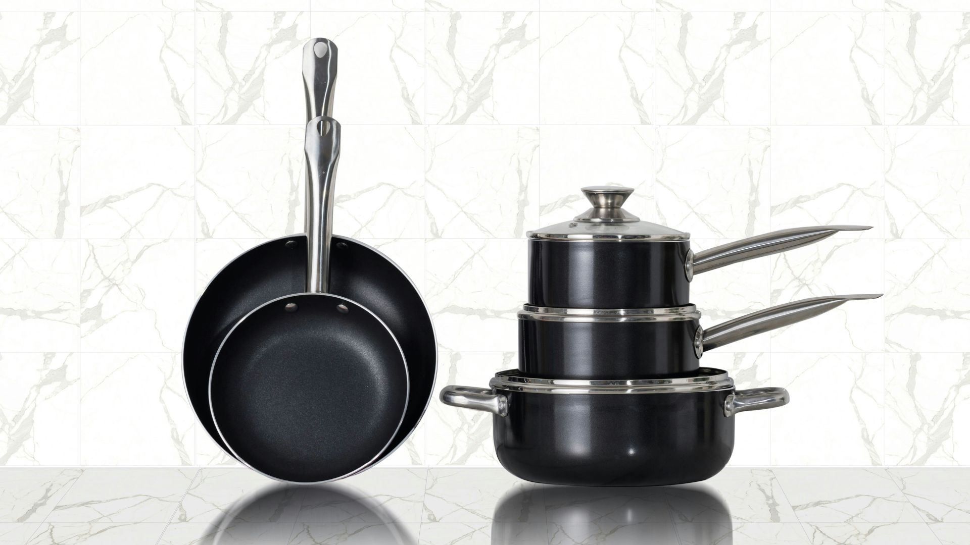 Three stainless steel cooking pots on white ceramic tiles