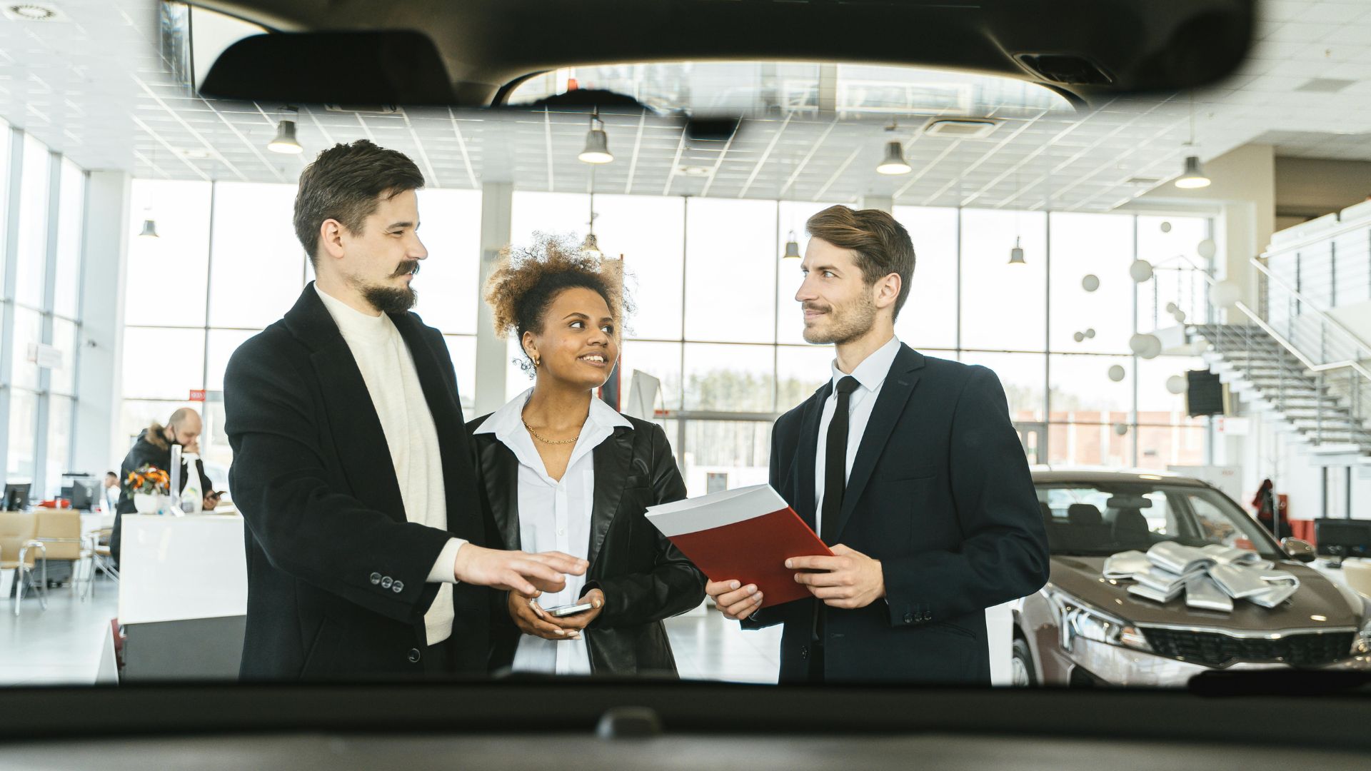 Car salesman talking with a couple inside a dealership