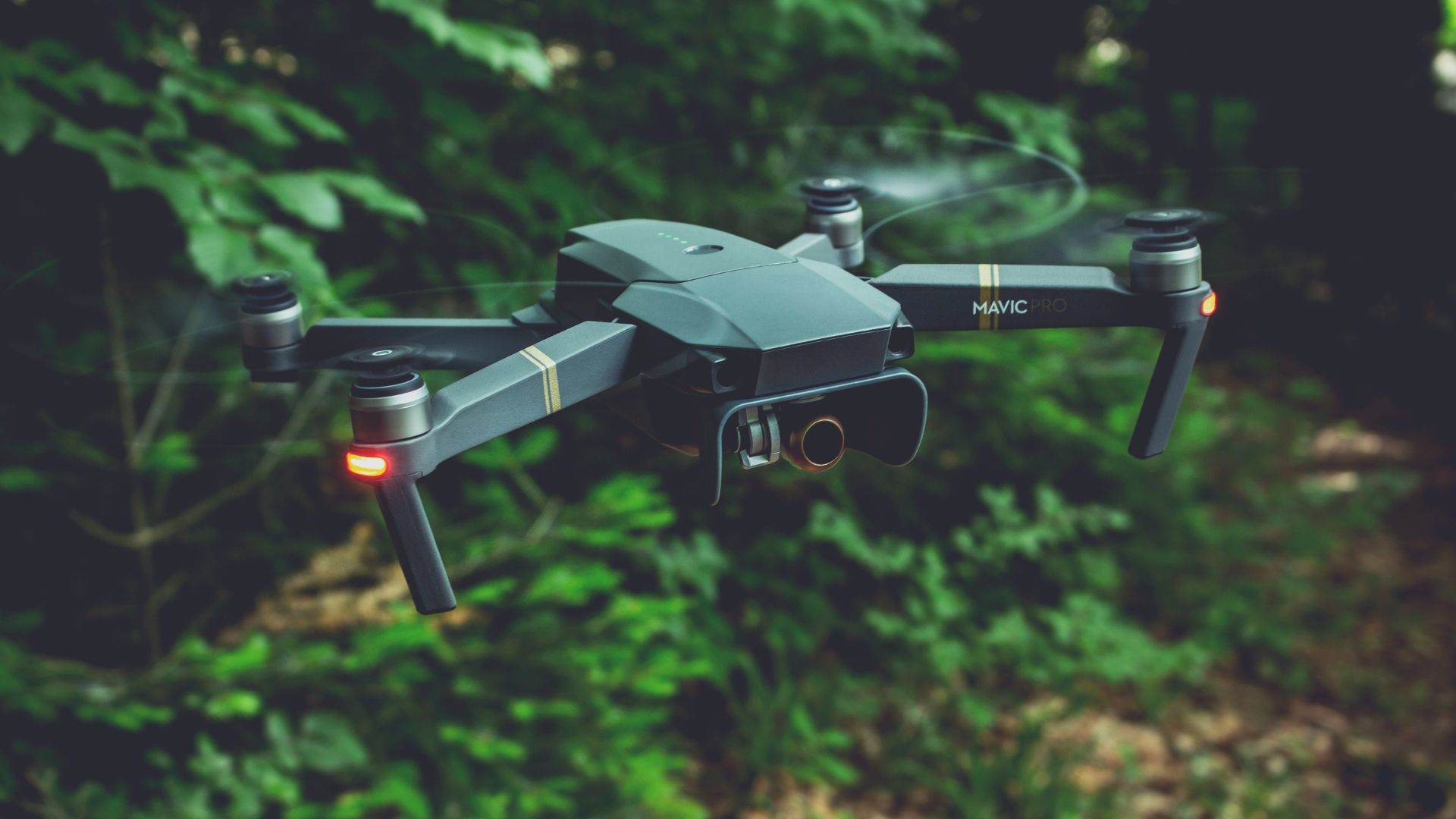 Gray quadcopter drone hovering outdoors