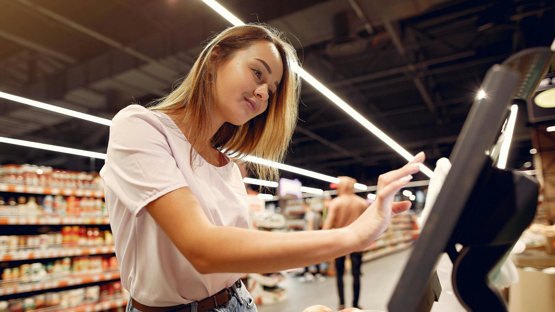Woman weighing produce on an electronic scale in a supermarket