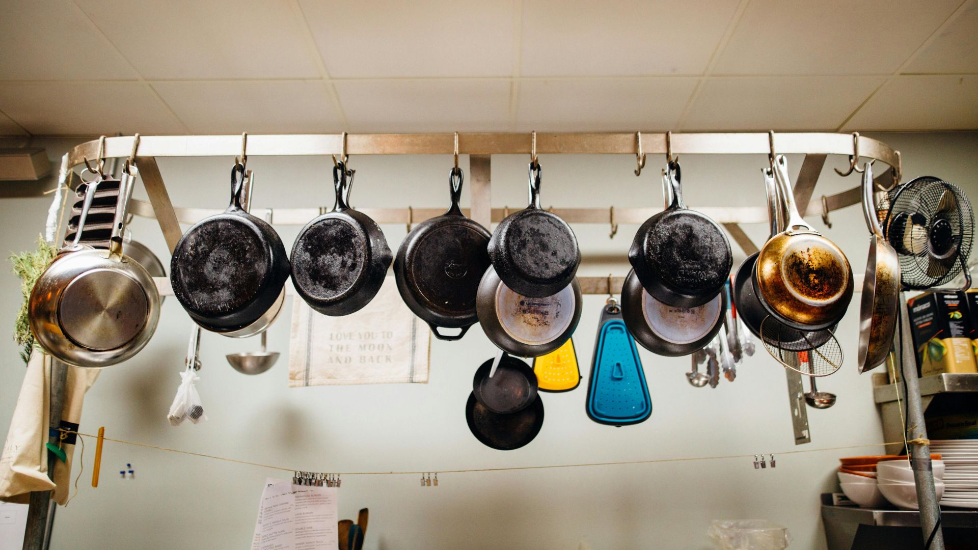 Assorted frying pans hanging on a pot rack