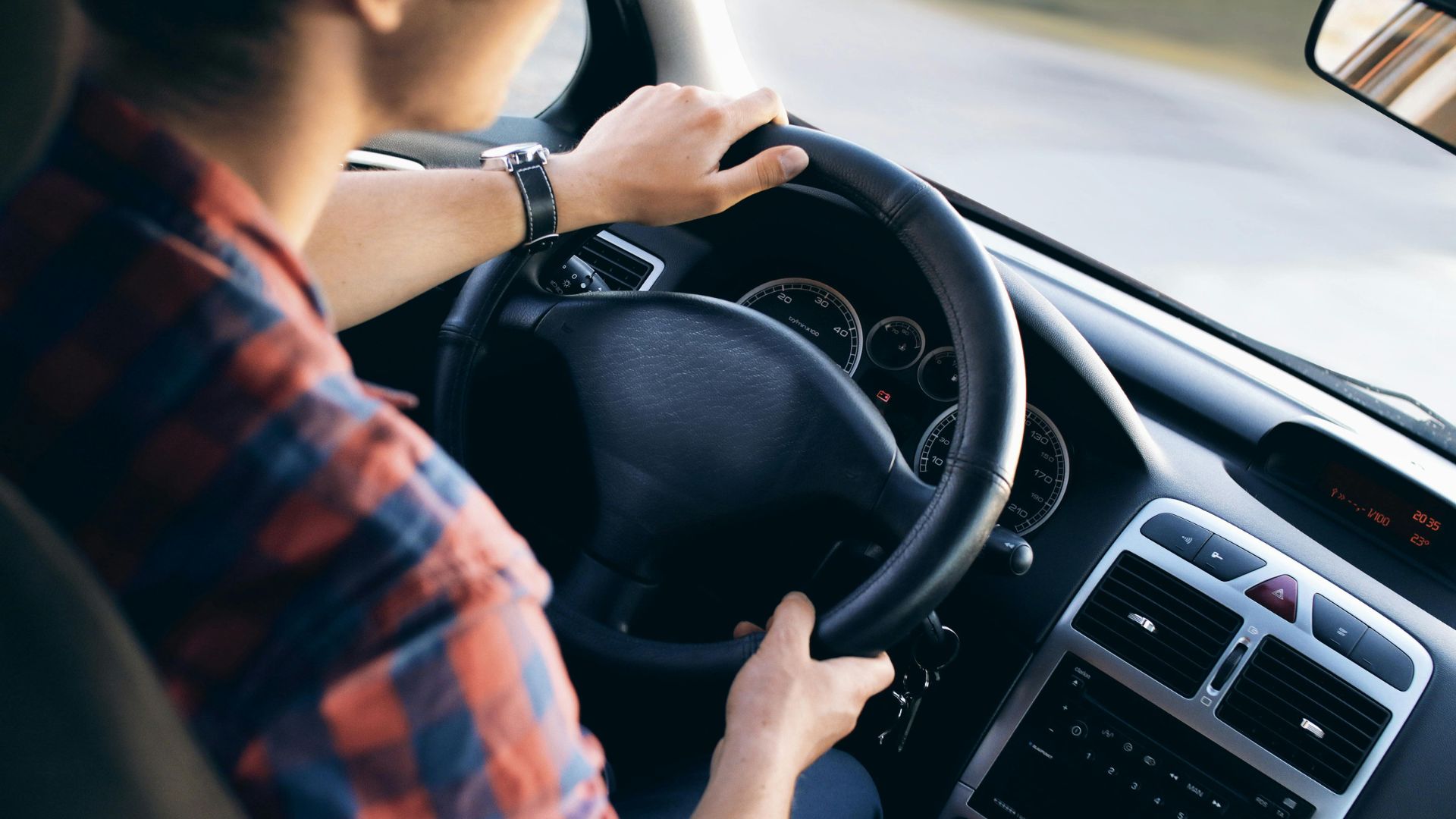Man sitting inside a vehicle holding the steering wheel