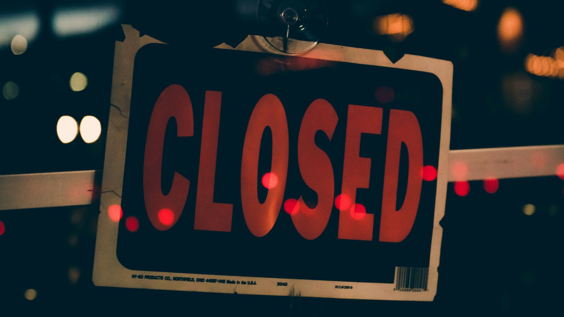 Red and black closed sign hanging on a glass door