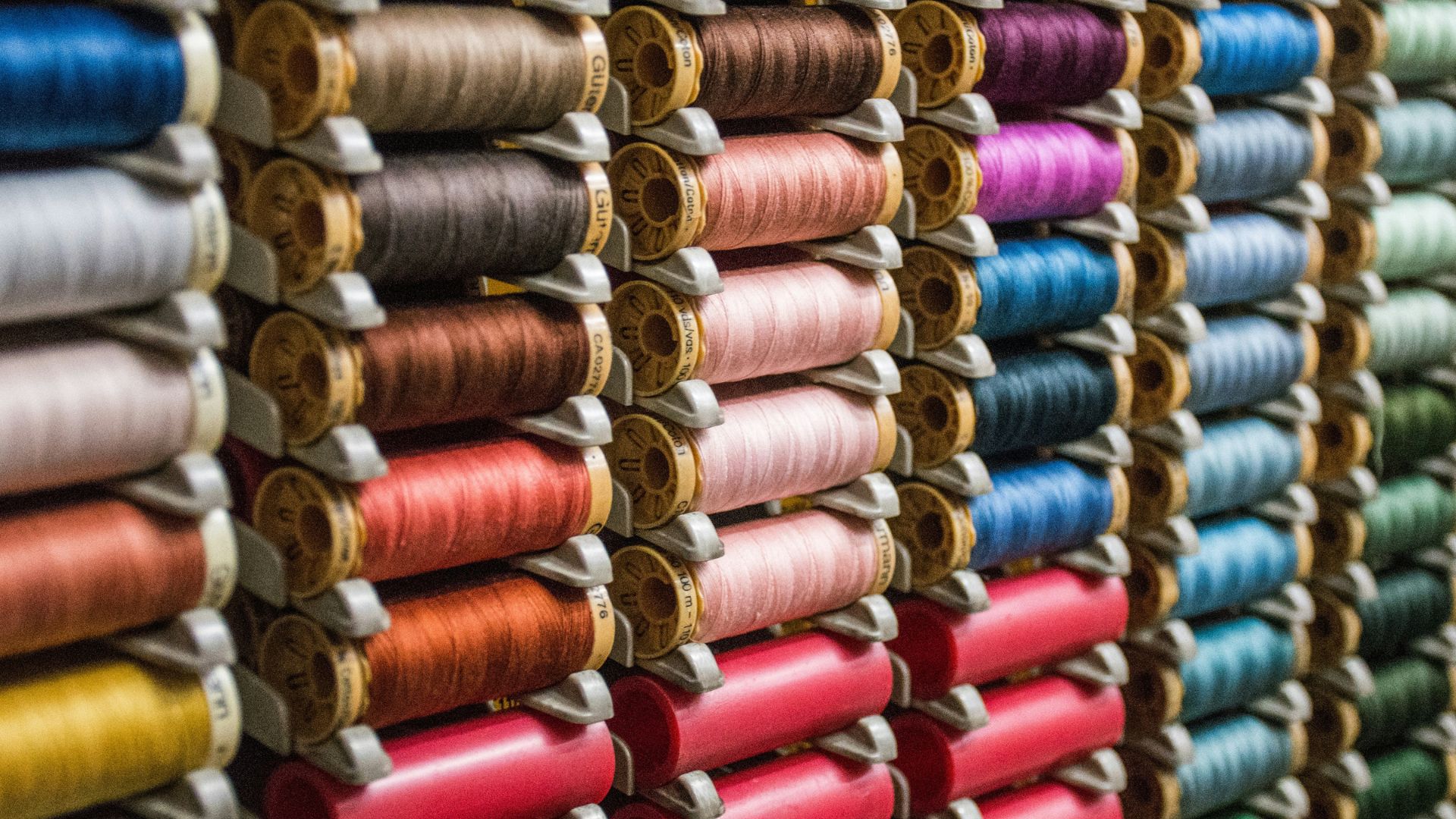 Spools of colorful thread stacked together on a factory shelf