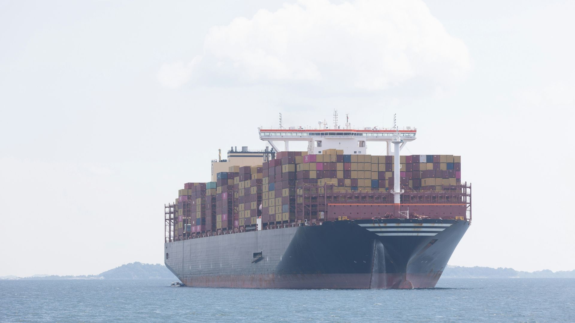 Cargo ship crossing open ocean under clear sky