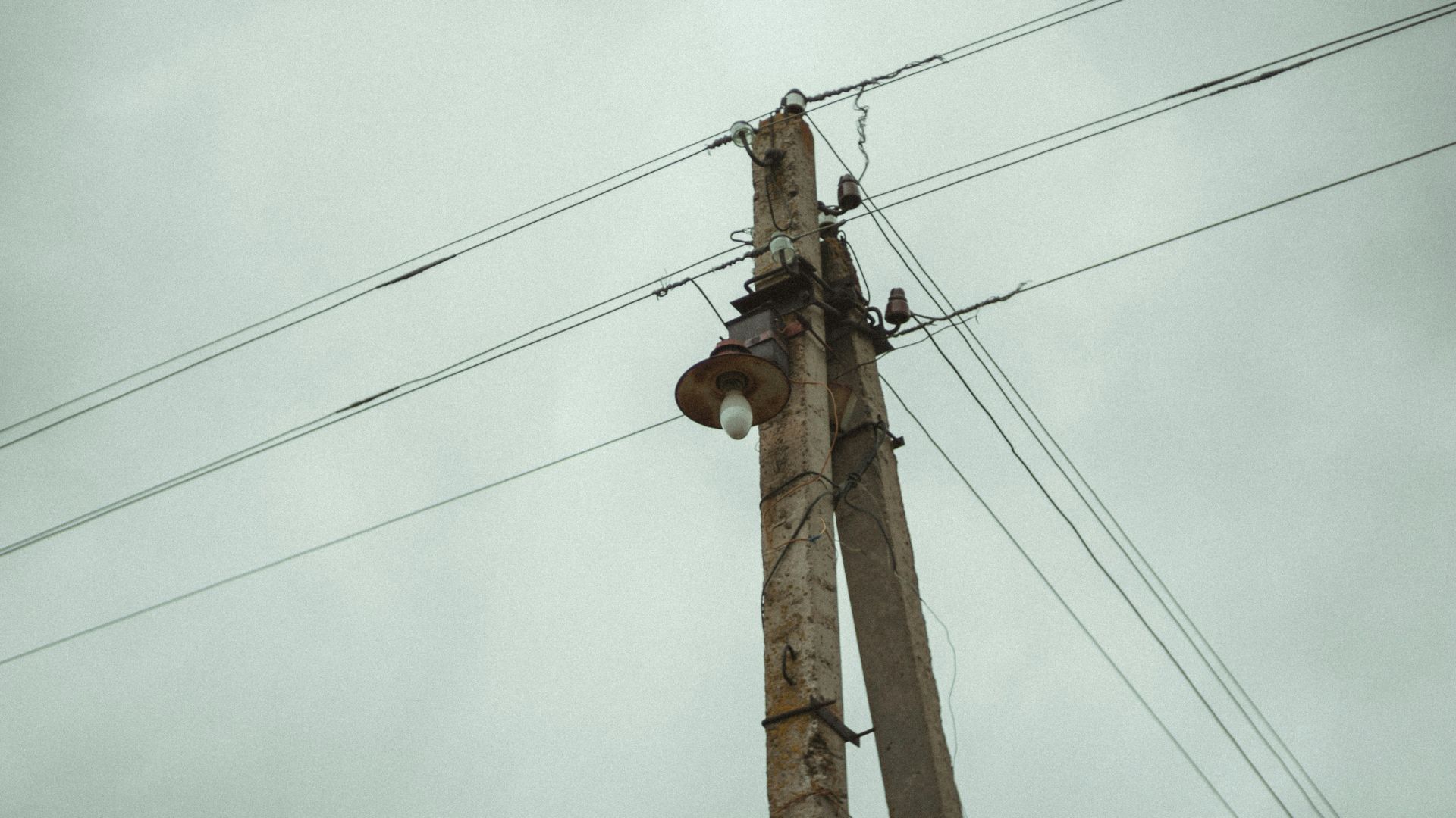 Utility pole with multiple power lines against a cloudy sky