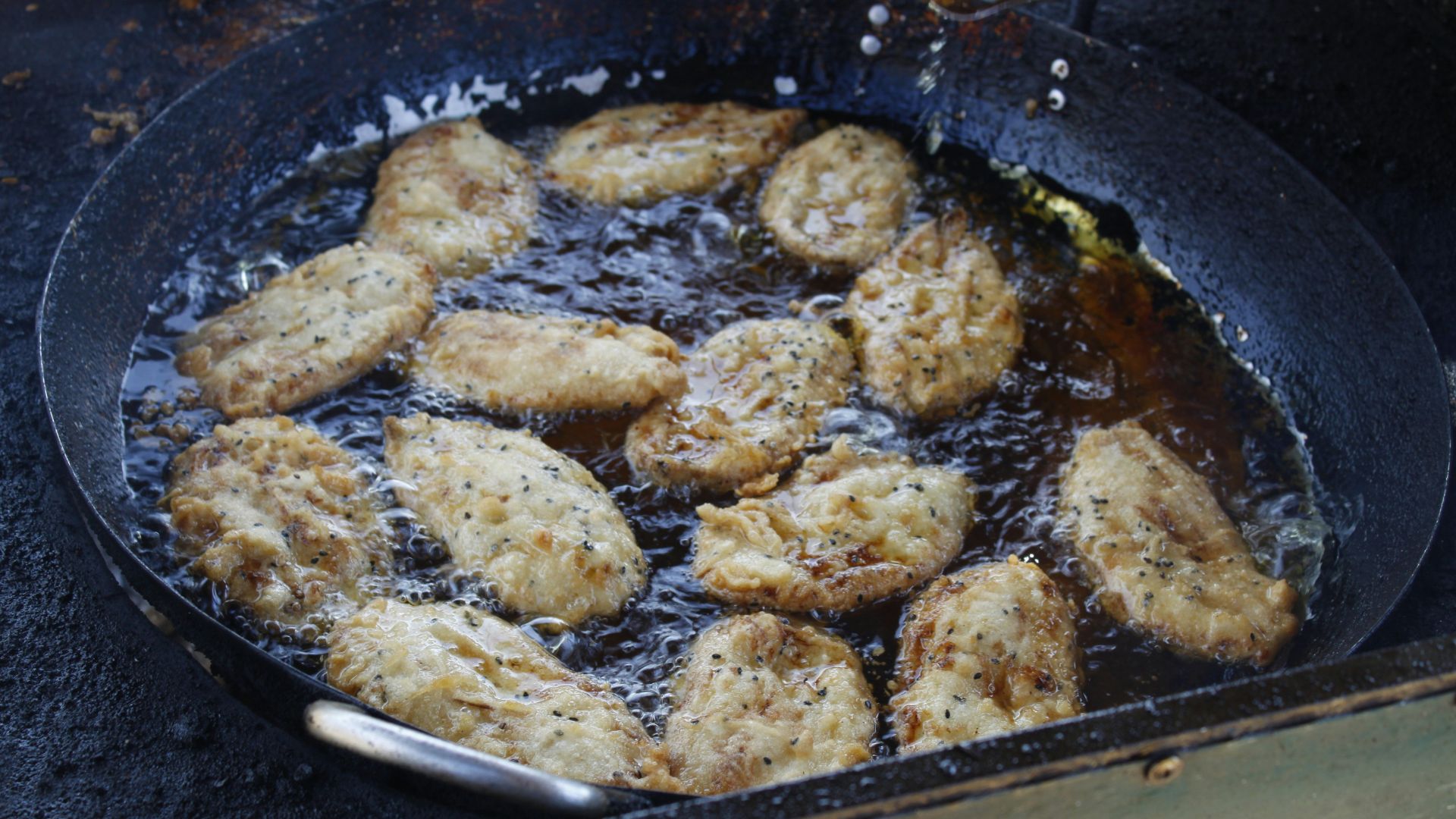 Meat frying in a wok with oil and steam rising from it