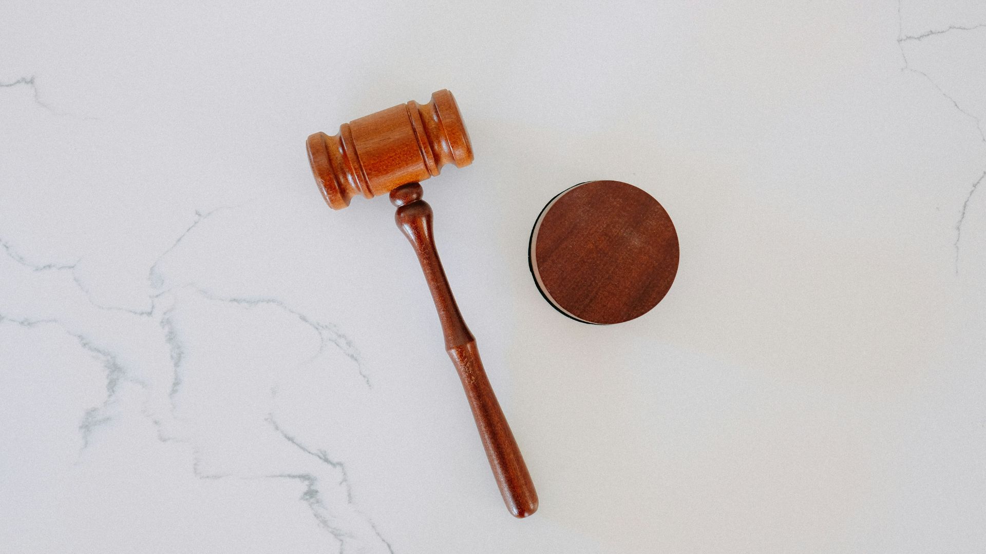 Wooden judge’s gavel resting beside a legal pipe on white background