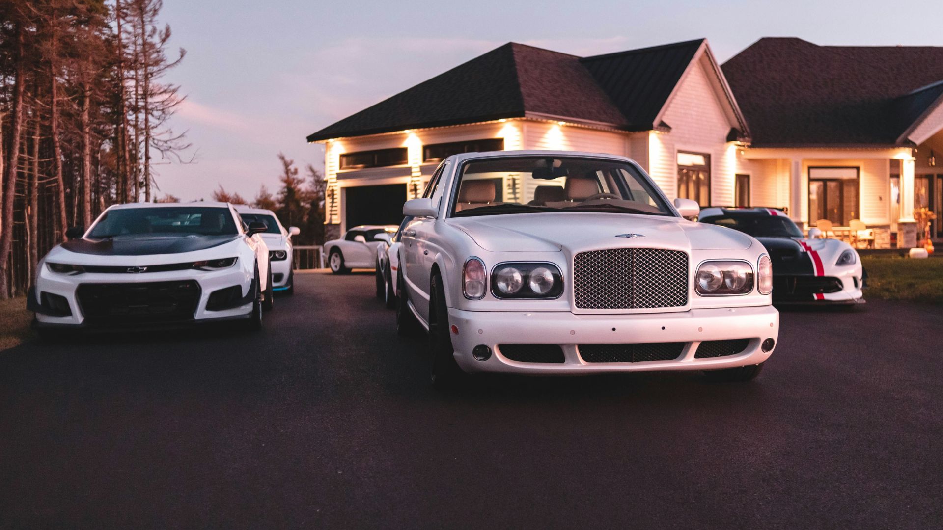 White luxury car driving on a paved road through scenic landscape