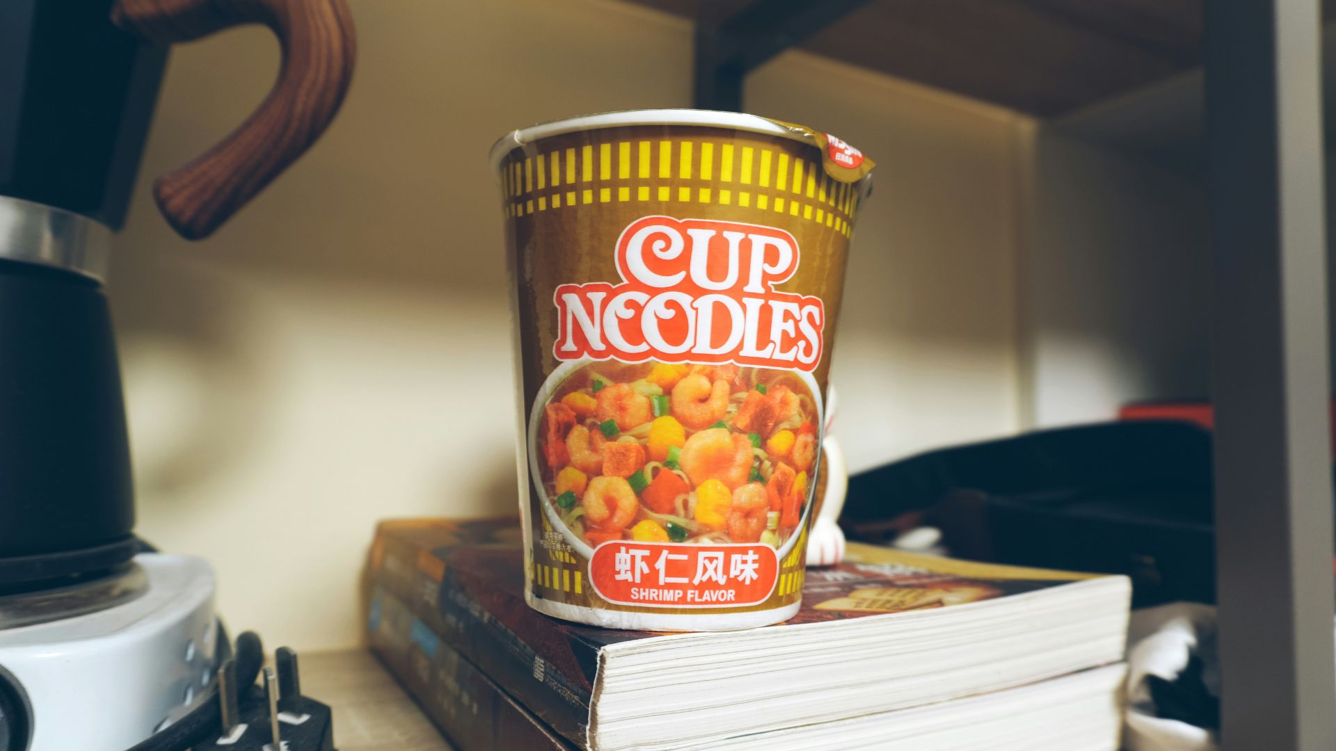 Cup of instant noodles resting on a stack of books