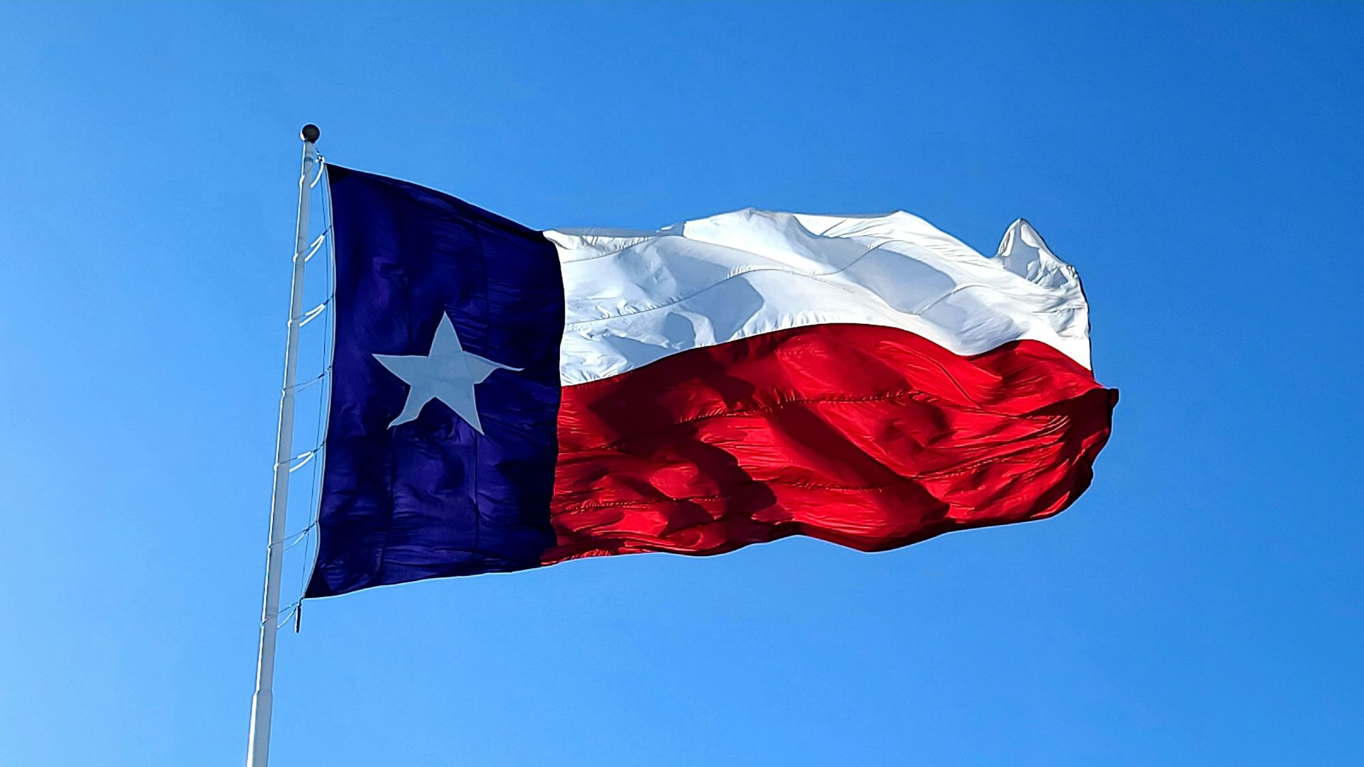 American flag waving against a clear blue sky