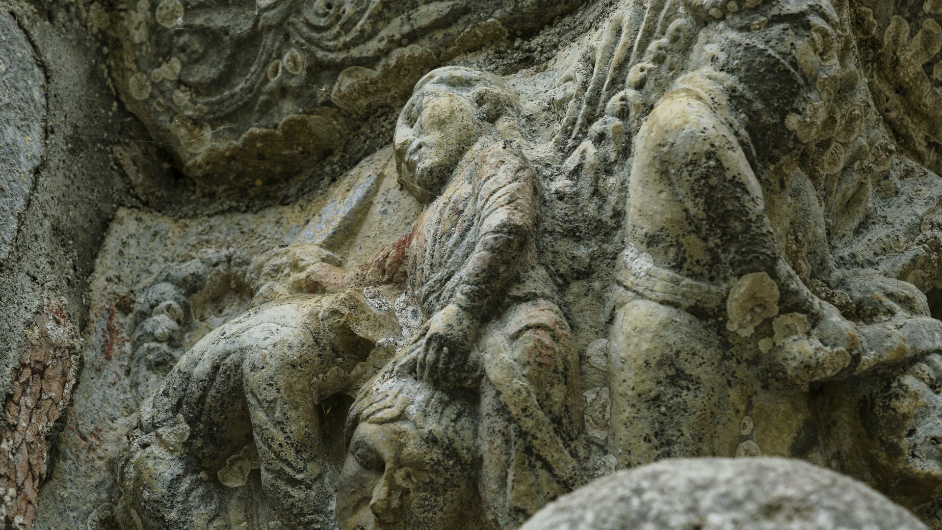 Stone sculpture of ancient figures with detailed faces carved into rock