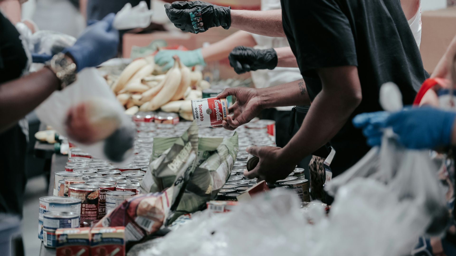 Man in black shirt handing out Coca-Cola bottles at a donation site