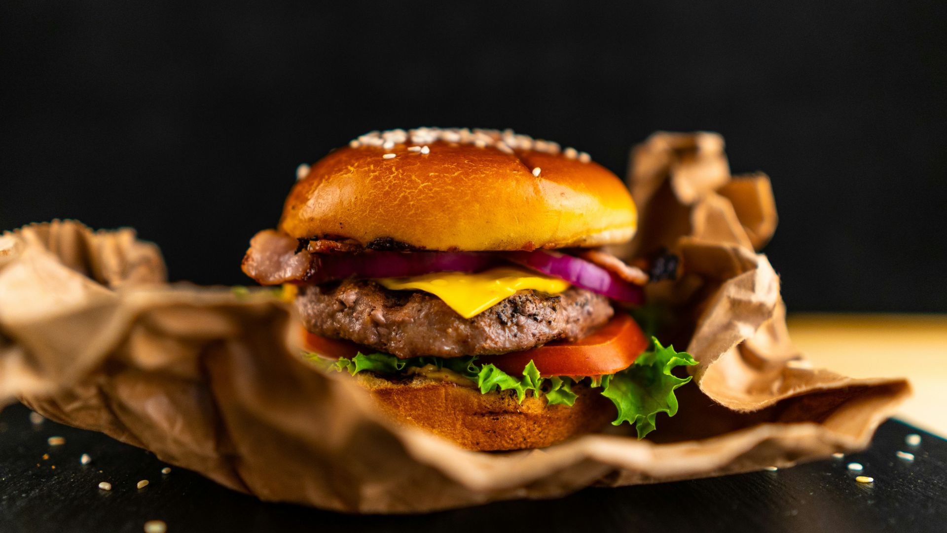 Close view of a burger with lettuce and tomato on a wooden board