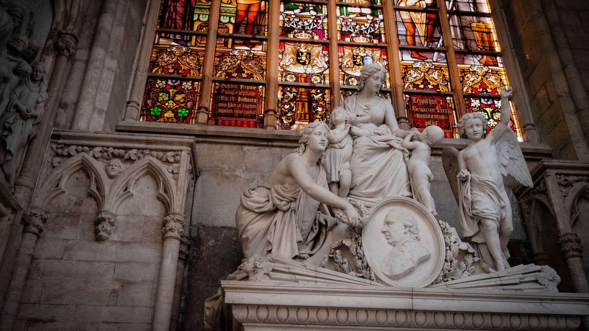 White stone statue of a saint standing outside a historic building in daylight