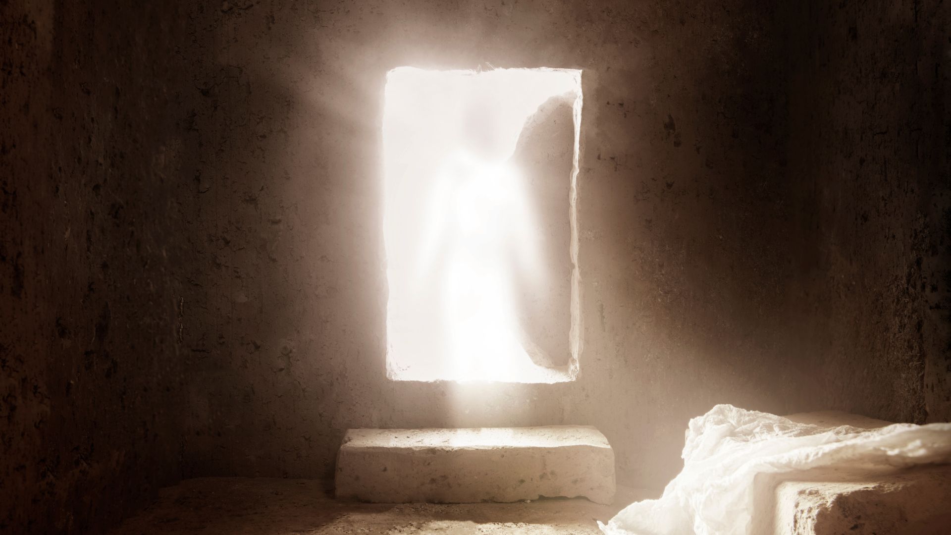 Tomb of Jesus Christ with light shining through the entrance at sunrise.