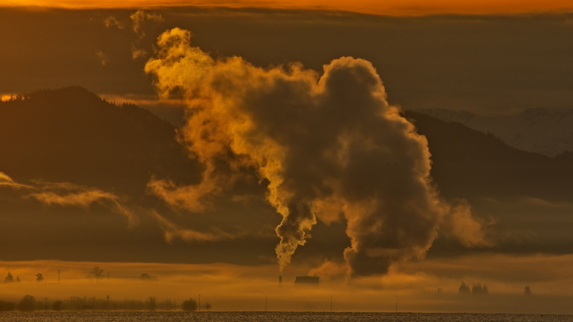 Thick plume of smoke rising from a large industrial pipe