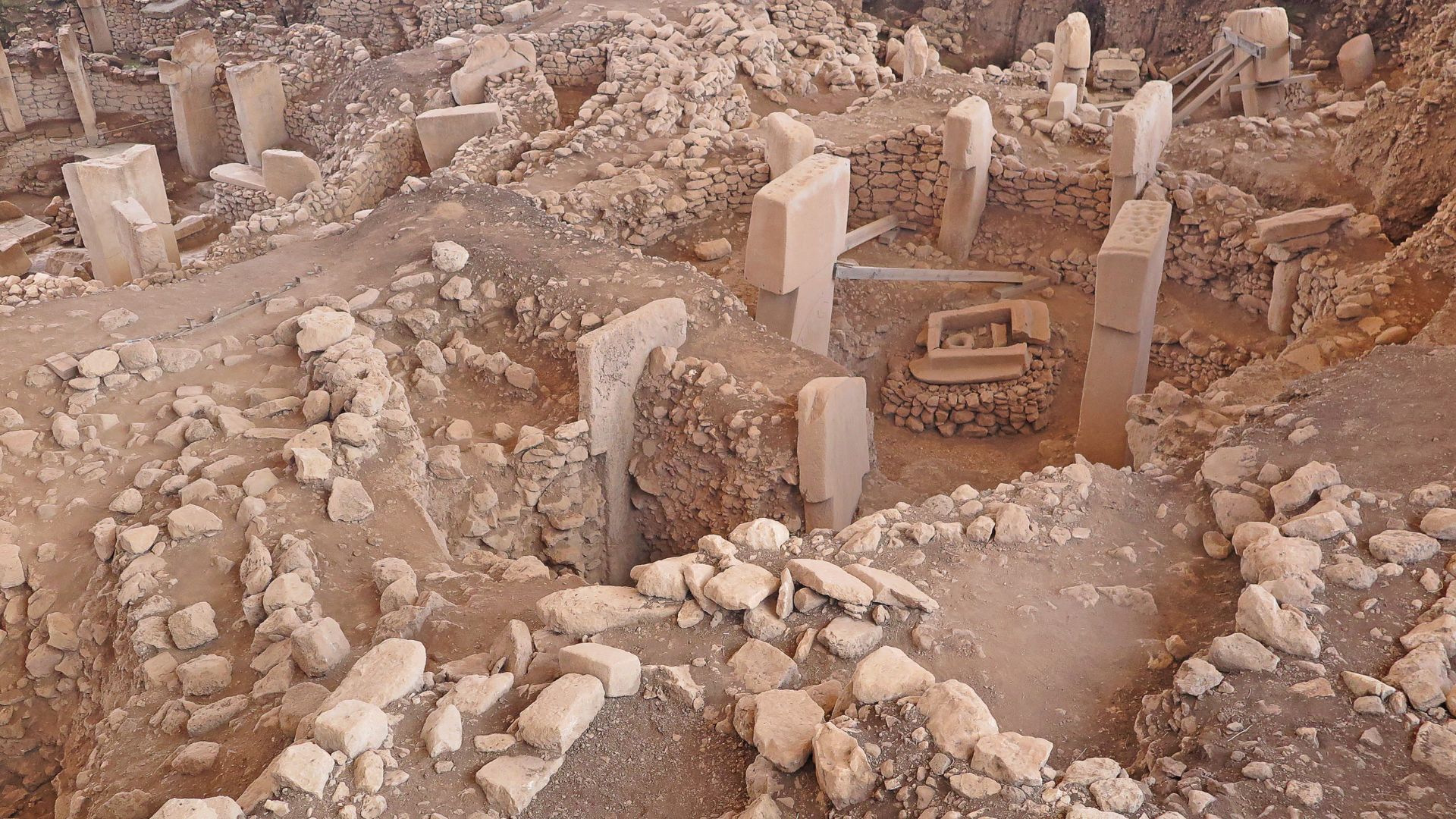 Archaeological excavation at Gobekli Tepe with stone pillars and workers in a sheltered dig area