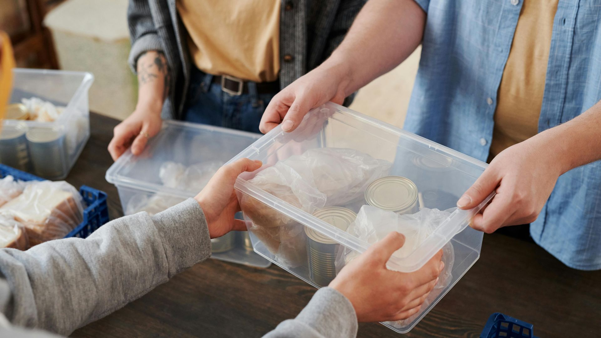 Person handing over a box filled with food items at a donation drive