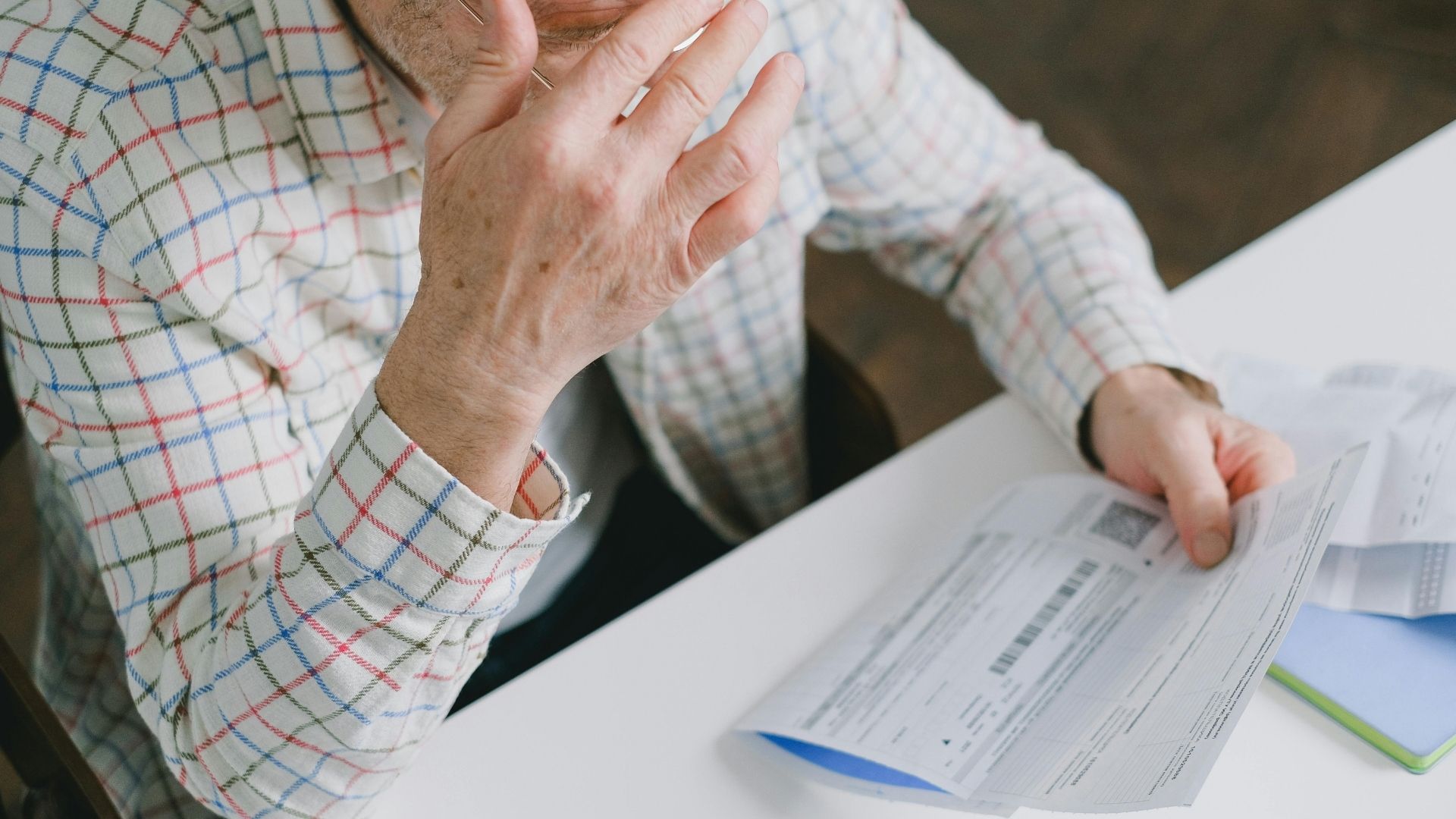 Elderly man reviewing financial papers at a desk