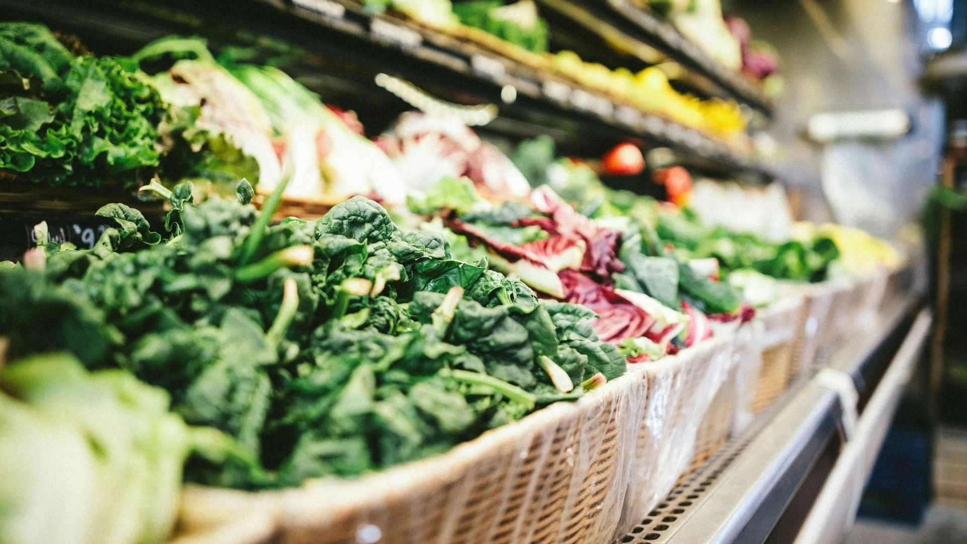 Grocery store produce section displaying rows of fresh vegetables on shelves