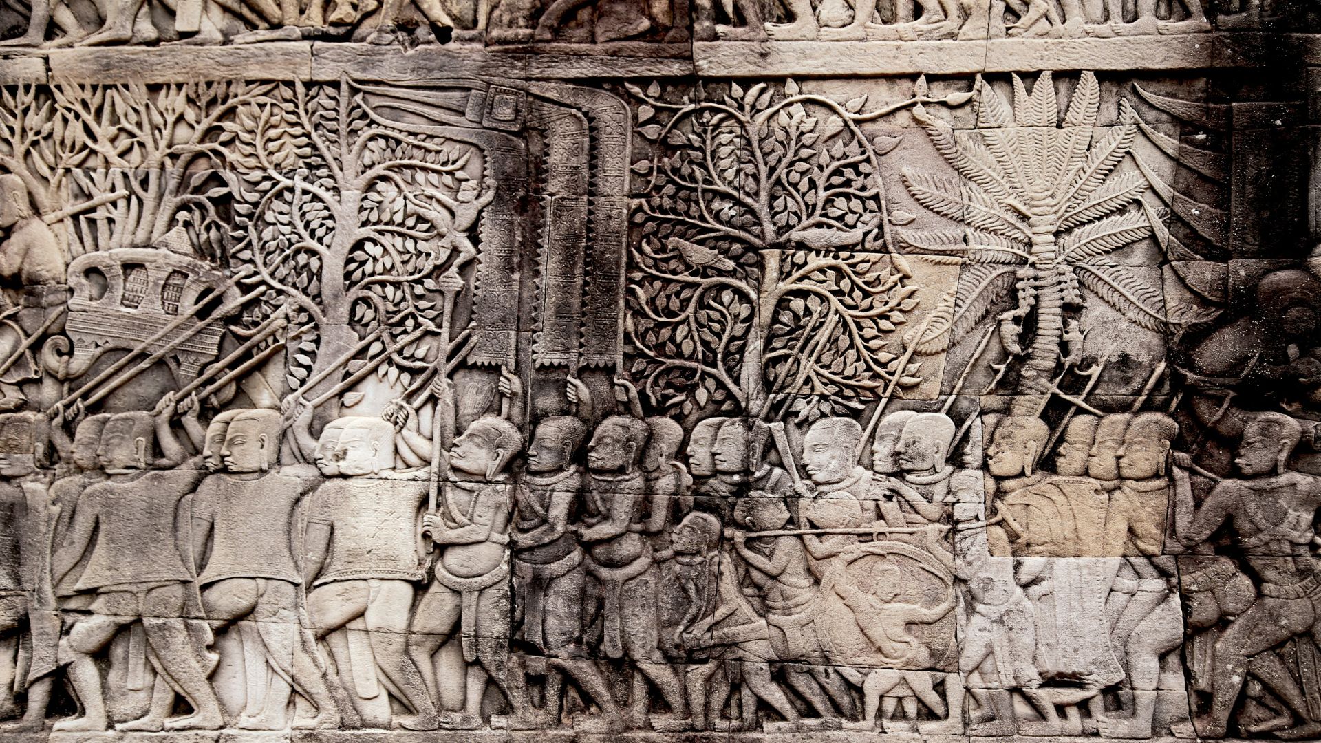 Stone relief showing people holding spears on an ancient wall