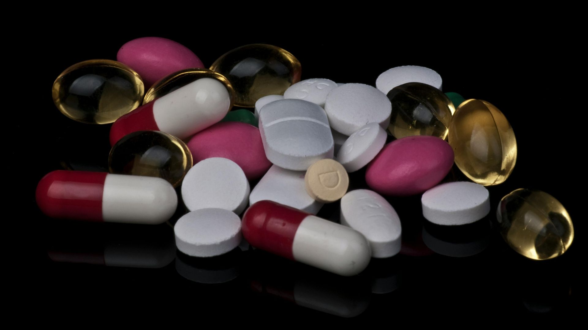 Assorted pills and tablets arranged on a black surface